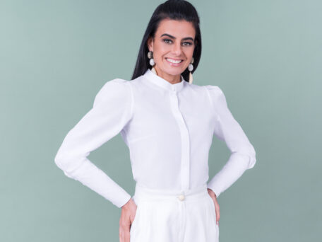 Elegante mulher com modelo de camisa branca feminina PIA Collection, estilo profissional, apresentando acessórios sofisticados, ideal para moda e estilo de vida.